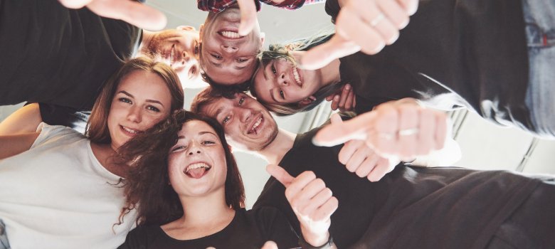 Happy group of friends with their hands together in the middle Happy group of friends with their hands together in the middle